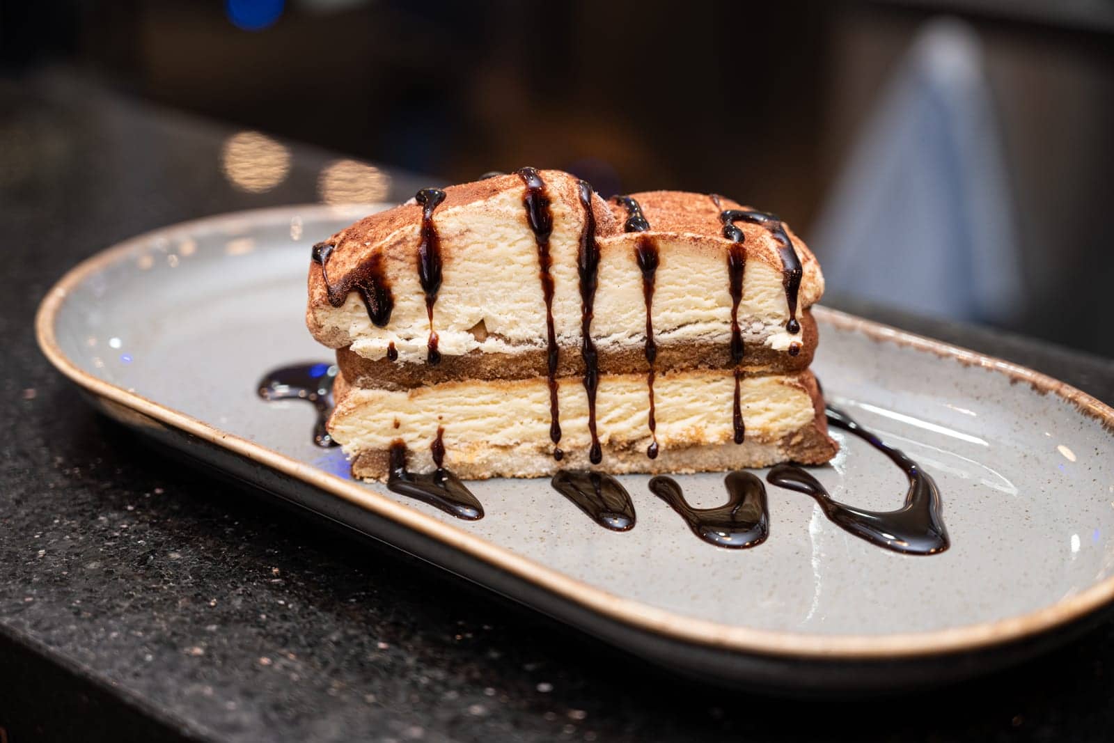 Slice of cheesecake drizzled with chocolate sauce