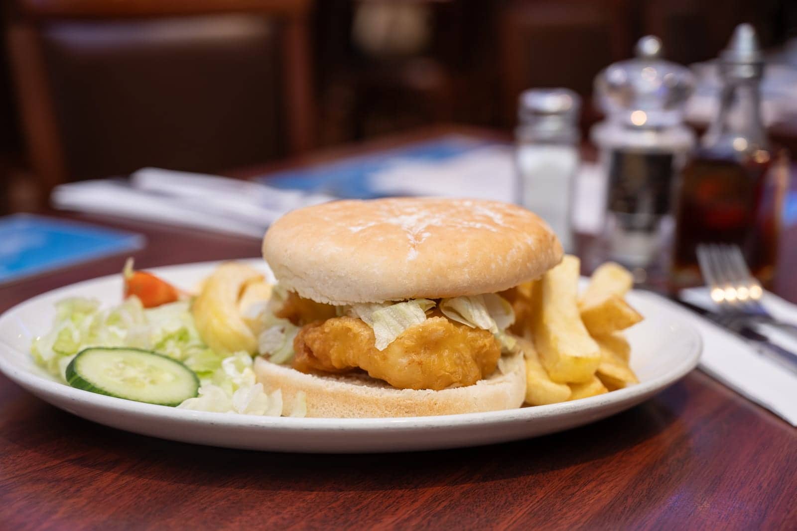 Fish burger in a toasted bun with chips and salad